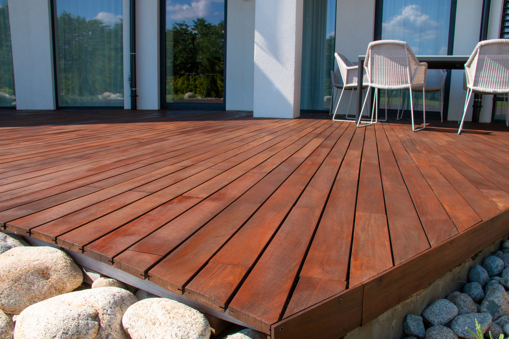 Freshly stained wooden deck with clean lines and an outdoor dining setup, demonstrating proper maintenance and repair techniques.