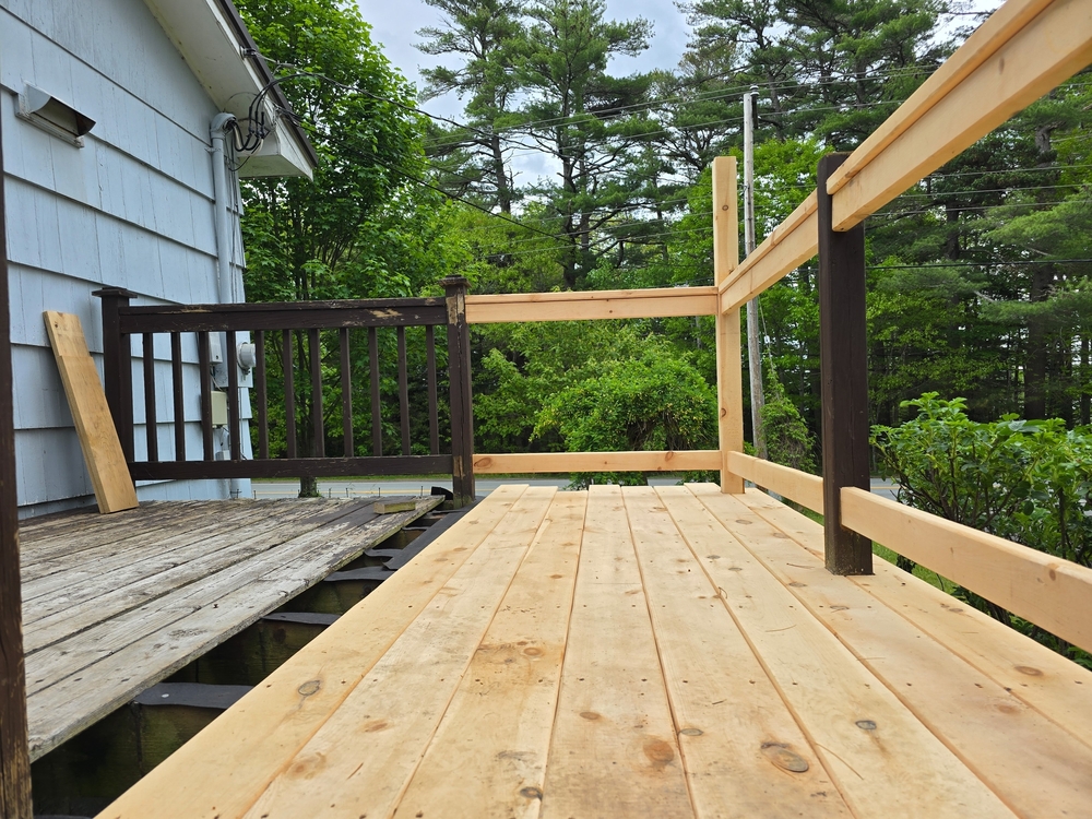 Partially repaired wooden deck with new boards and railings, illustrating key steps in ensuring deck safety.