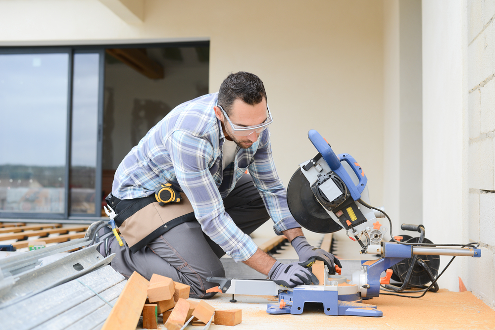 Professional contractor cutting wood with a miter saw during a deck installation project