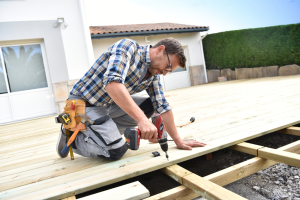 Homeowner using a power drill to build a wooden deck – Step-by-step deck construction guide