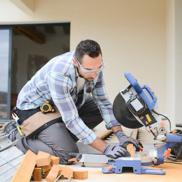 Professional contractor cutting wood with a miter saw during a deck installation project
