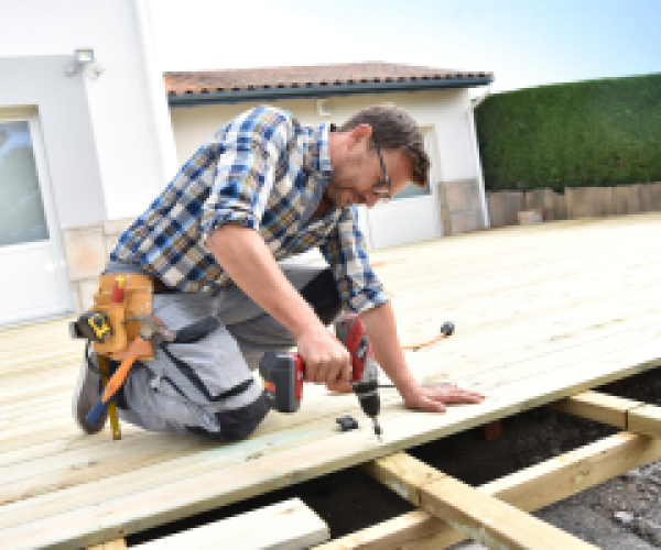 Homeowner using a power drill to build a wooden deck – Step-by-step deck construction guide